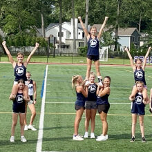 Cheerleaders perform supported stunts on the field